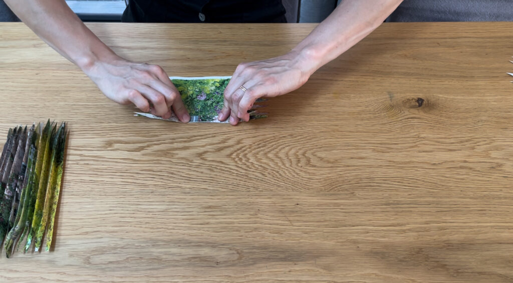 Woman folding piece of coloured paper into harmonica folds