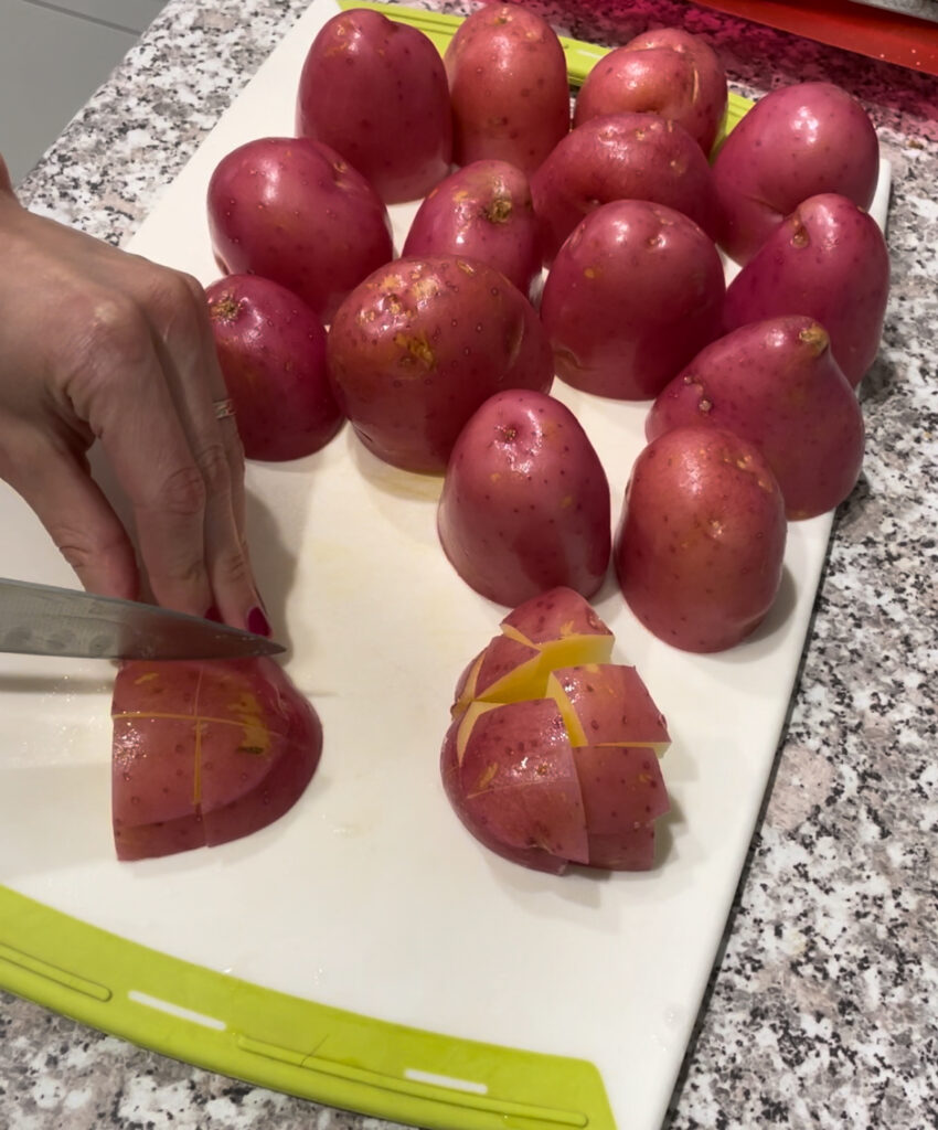 Woman cutting red potatoes on white chopping board