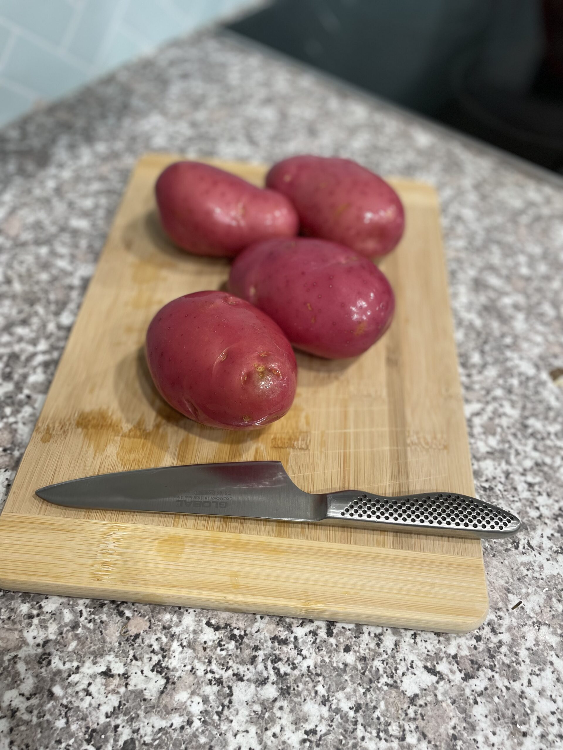 Red roasting potatoes on wooden chopping board