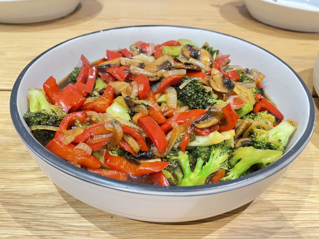 Stir fry of vegetables in white bowl on wooden table