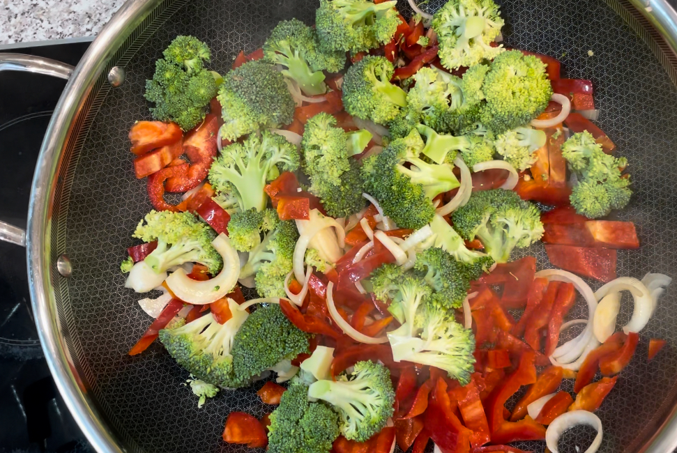 Wok filled with broccoli, red capsicum, onion and mushrooms