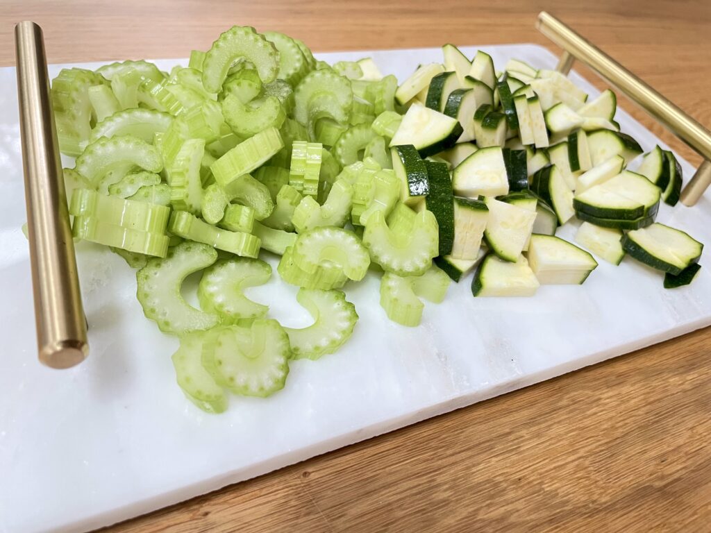 Sliced zucchini and celery on white tray with golden handles