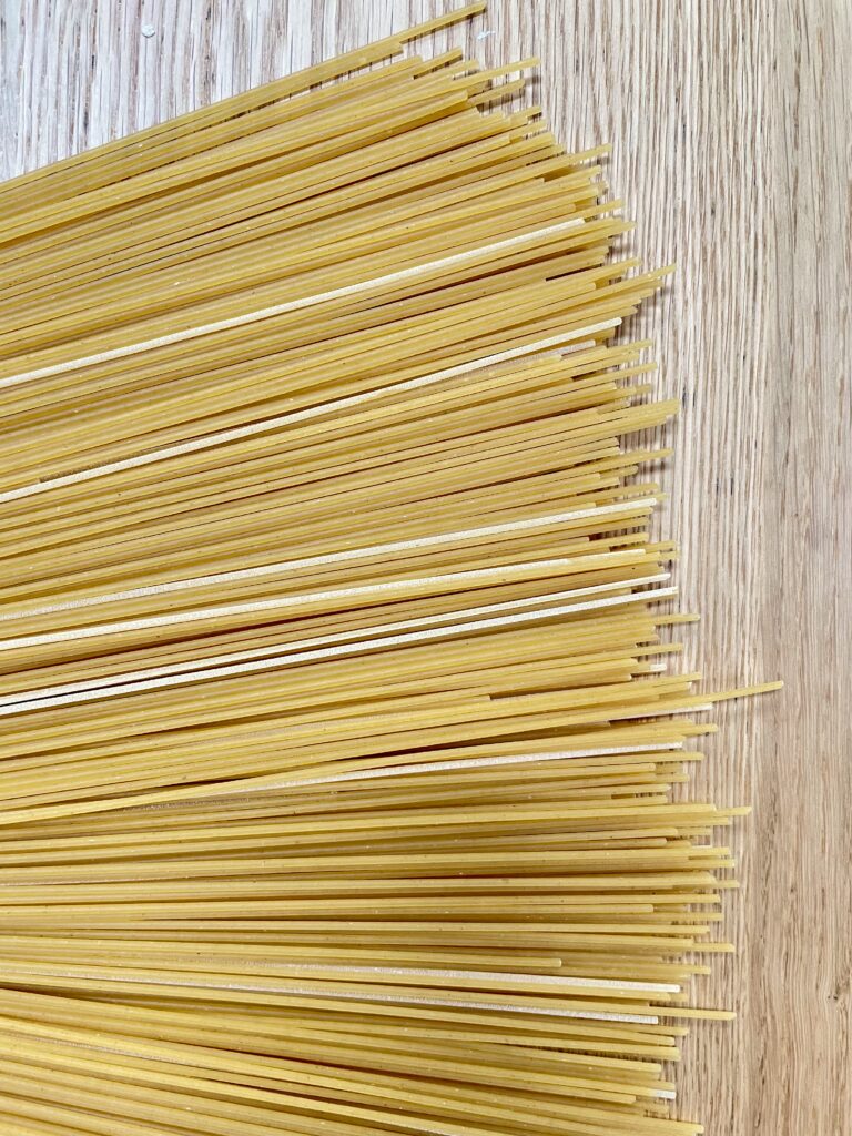 Uncooked spaghetti laid out on wooden table