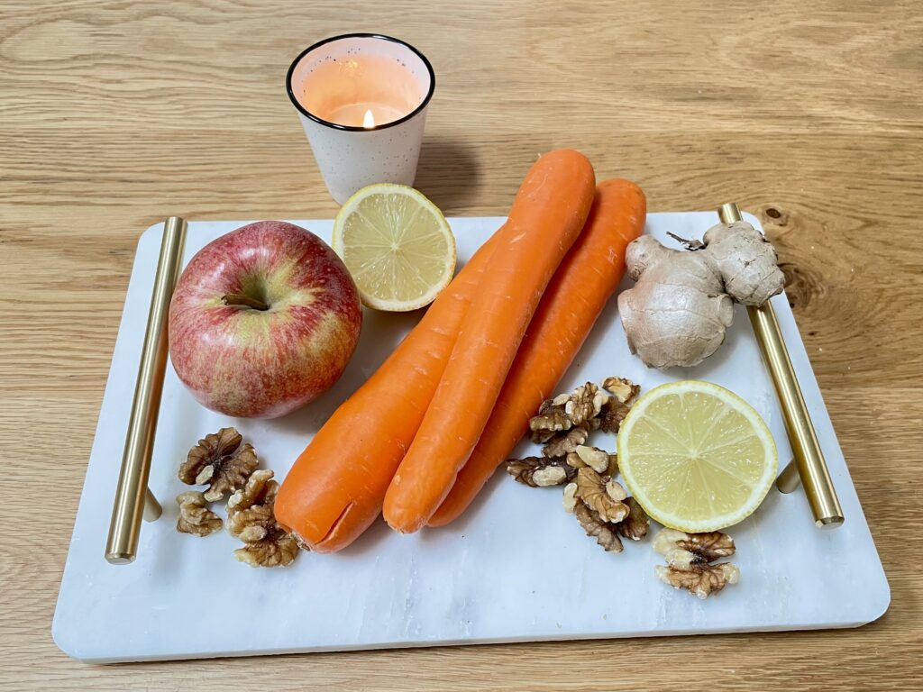 White marble tray with golden handles filled with produce, next to lit candle on wooden table