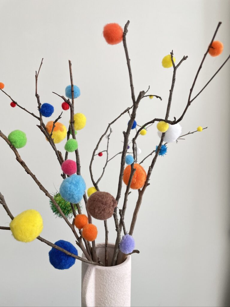 Pink vase with pom pom decorated branches