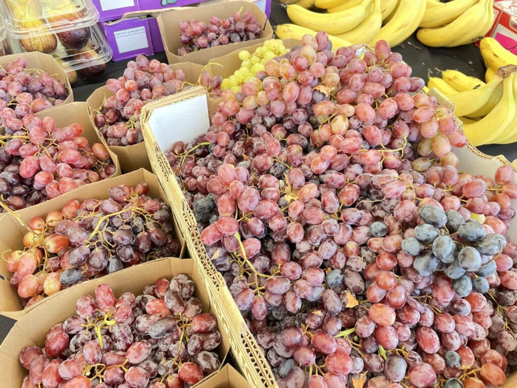 Simple market display of trays of red grapes and bananas