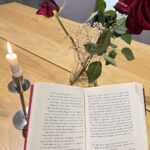 Open book for reading in front of candle and flowers