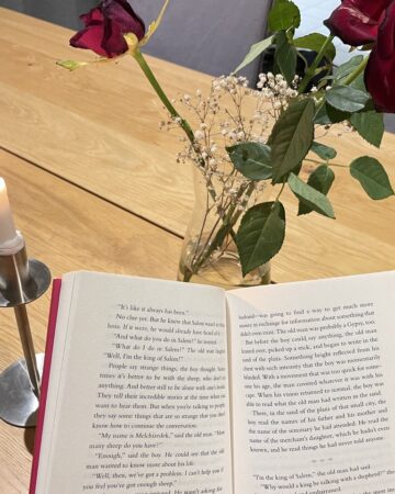 Open book for reading in front of candle and flowers