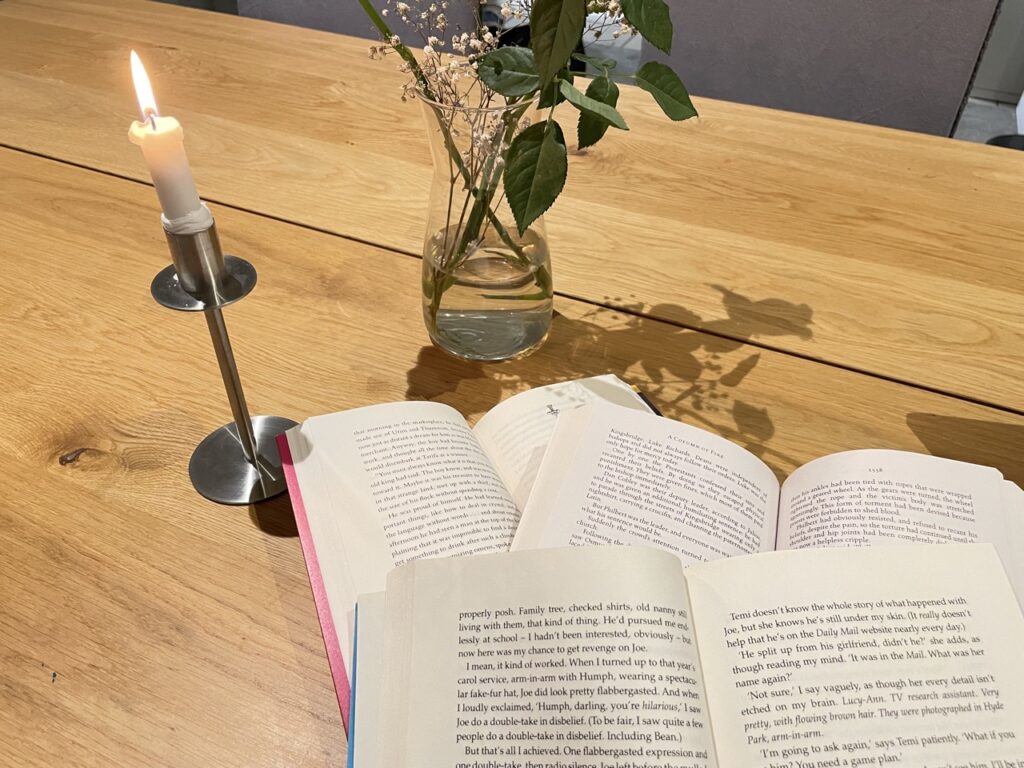 Three open books stacked in front of candle and flowers for best time to read