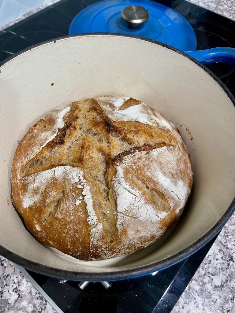 Blue dutch oven with rustic rye sourdough loaf inside