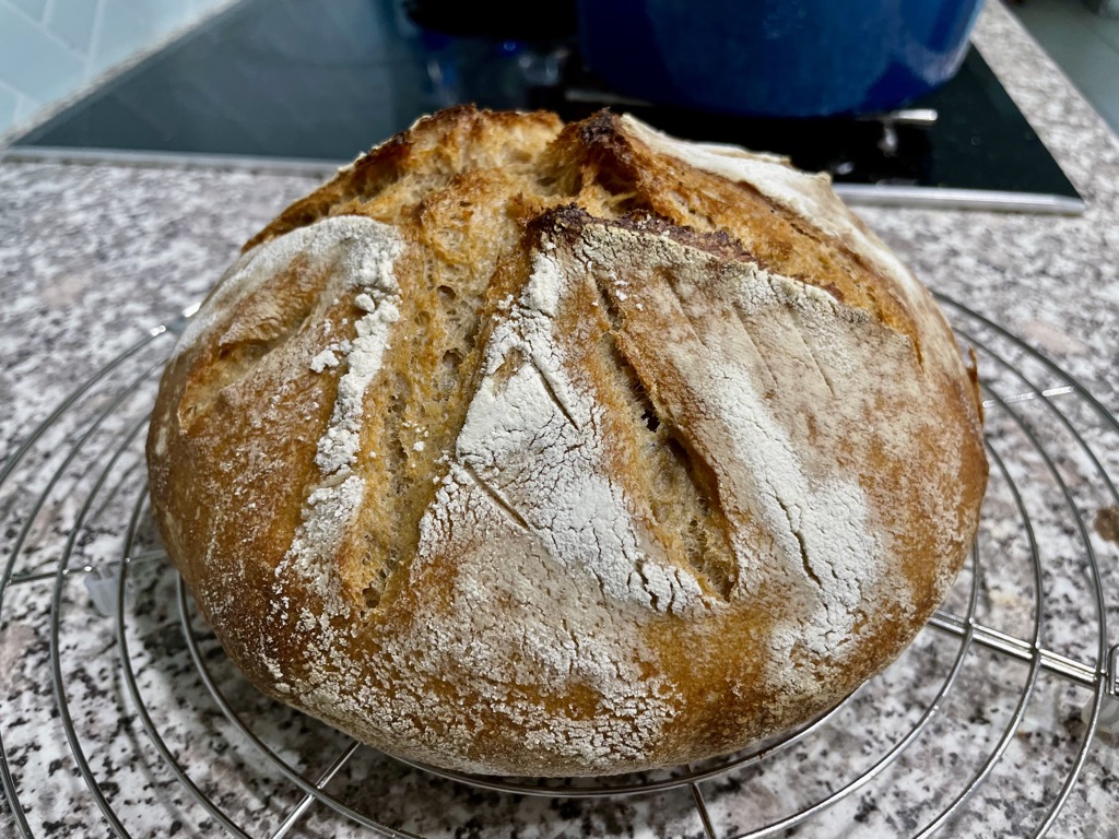 Rustic sourdough loaf on round cooling rack on kitchen bench