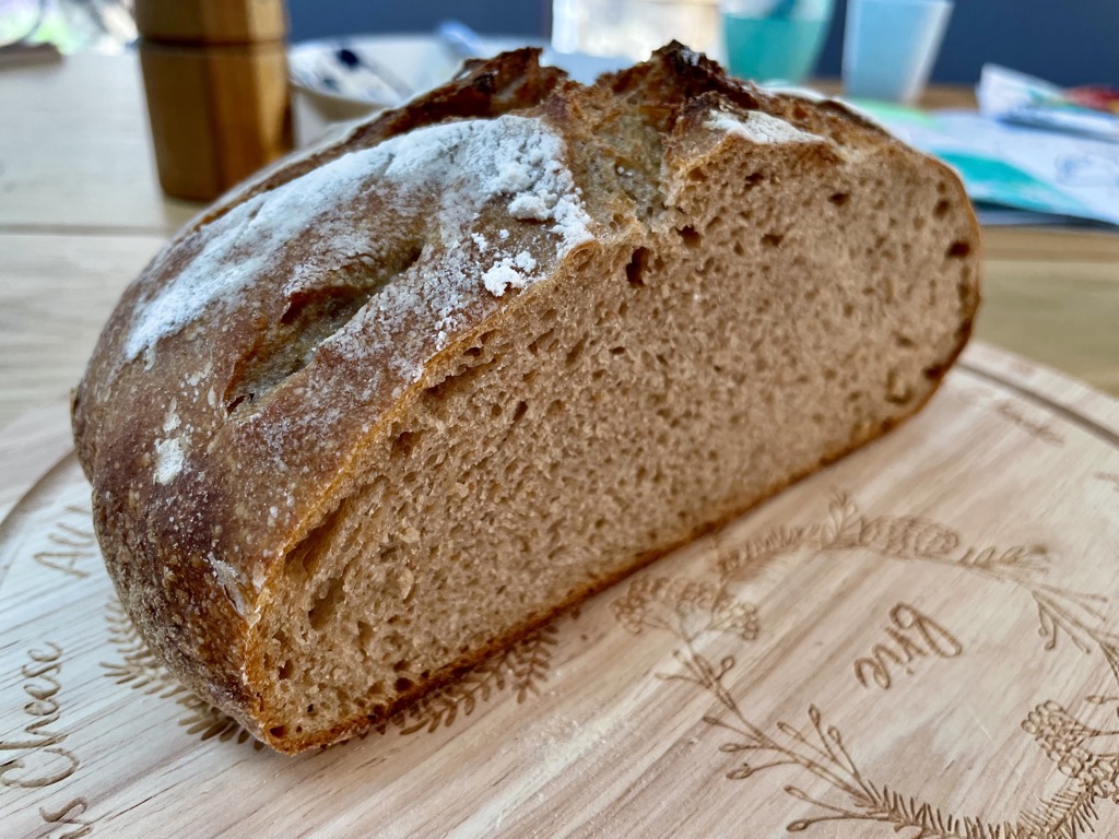 Half a loaf of whole wheat rye sourdough bread on wooden board