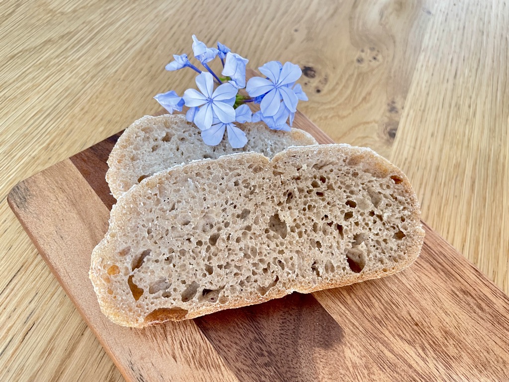 Two slices of rye sourdough with blue flowers on wooden board