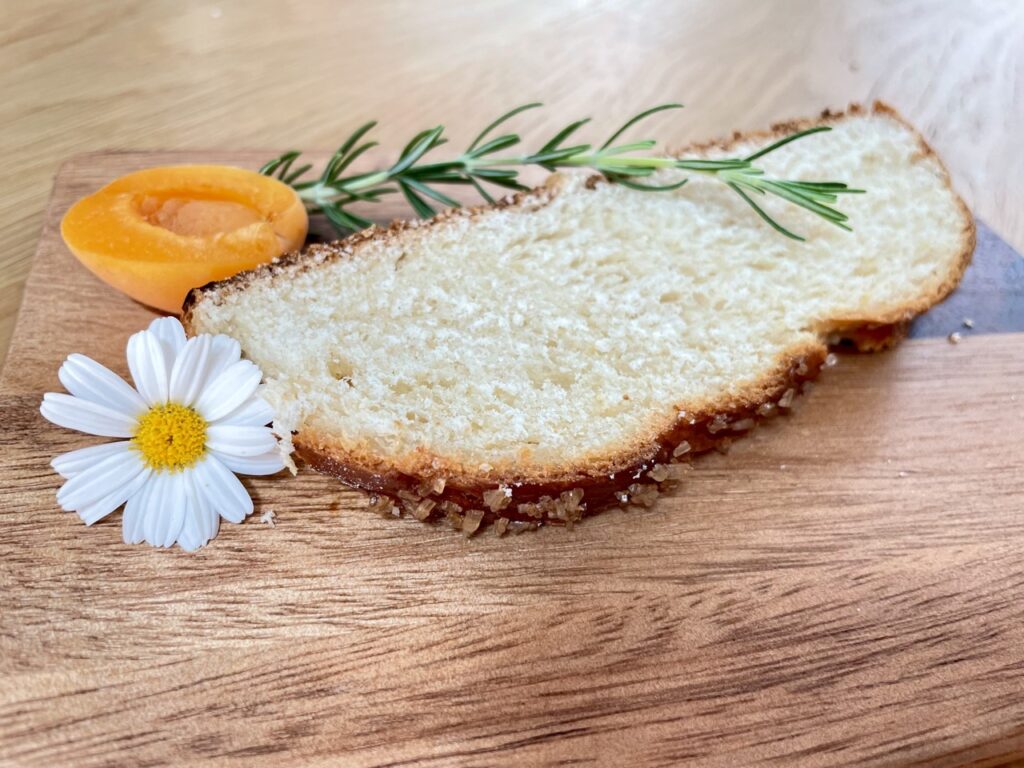 Slice of Hefezopf On wooden board with flower and apricot