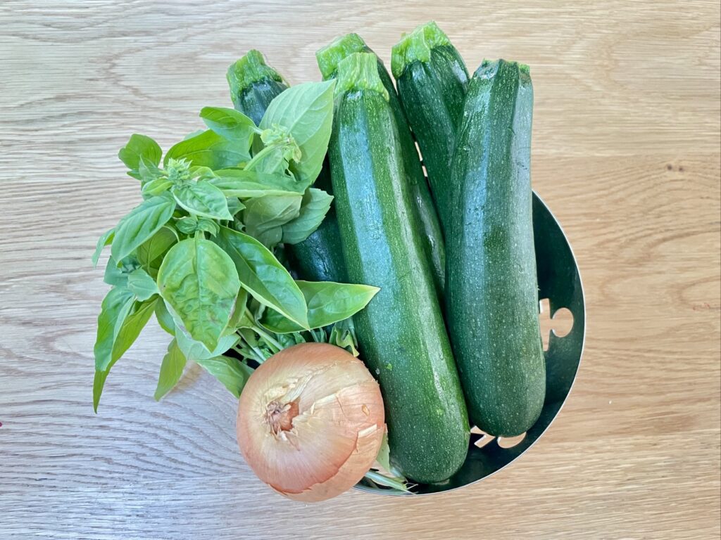 Silver bowl filled with courgette, basil and onion