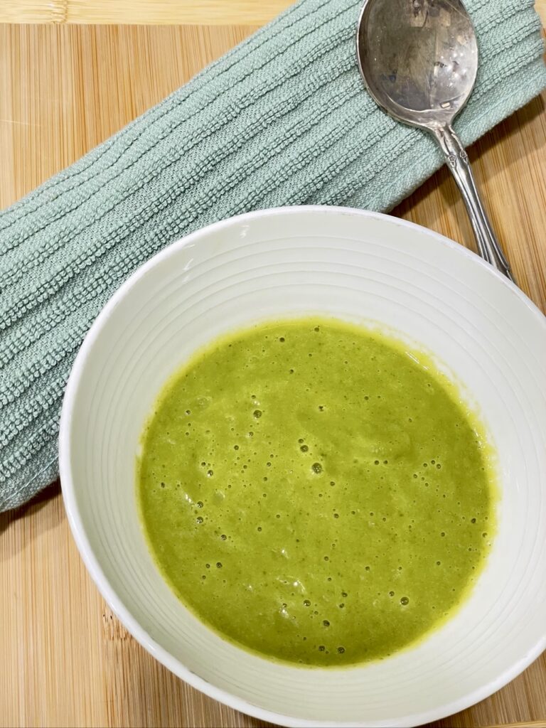 Bowl of zucchini soup with green napkin and silver spoon