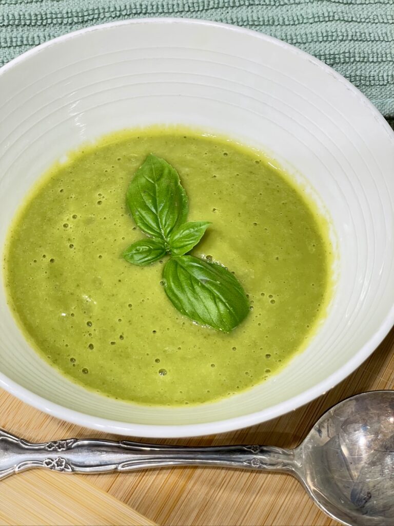 Bowl of Courgette and Basil soup with basil and silver spoon