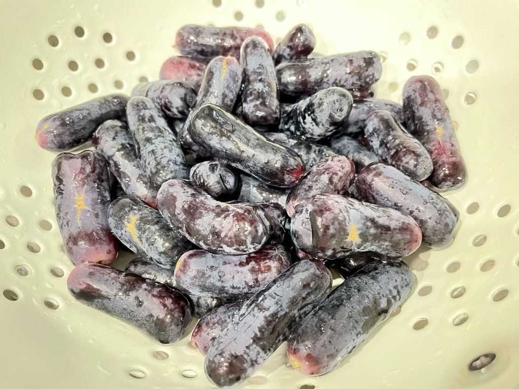 Long black grapes in cream coloured colander