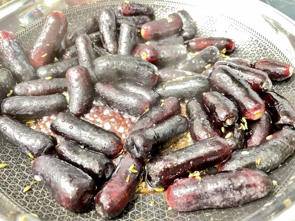 Grilling grapes in black frying pan with fennel seed