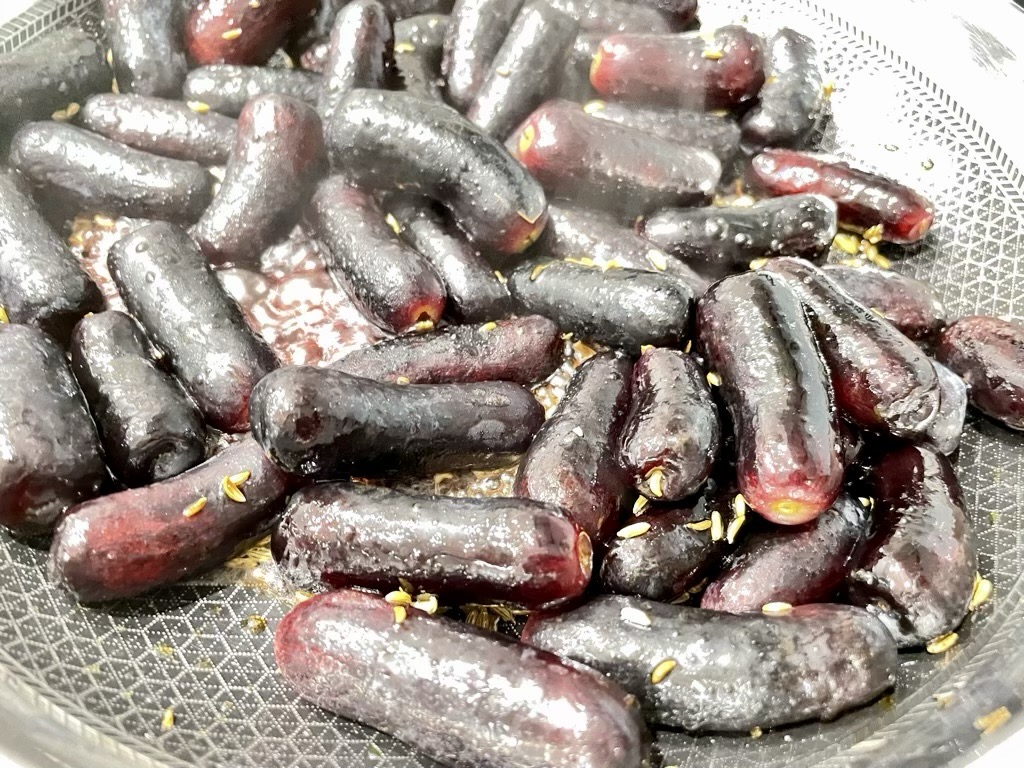 Black grapes and fennel seed sizzling in frying pan