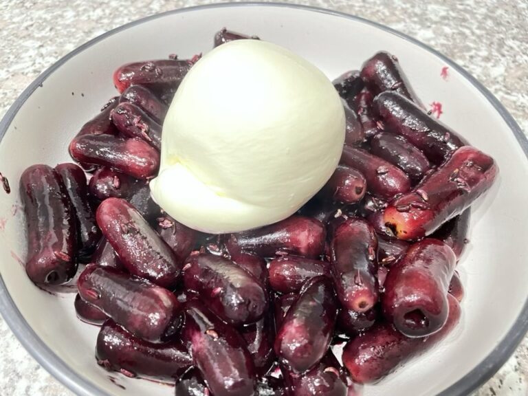 Close up shot of burrata sitting on grilled red grapes