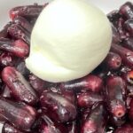 Close up shot of burrata sitting on grilled red grapes