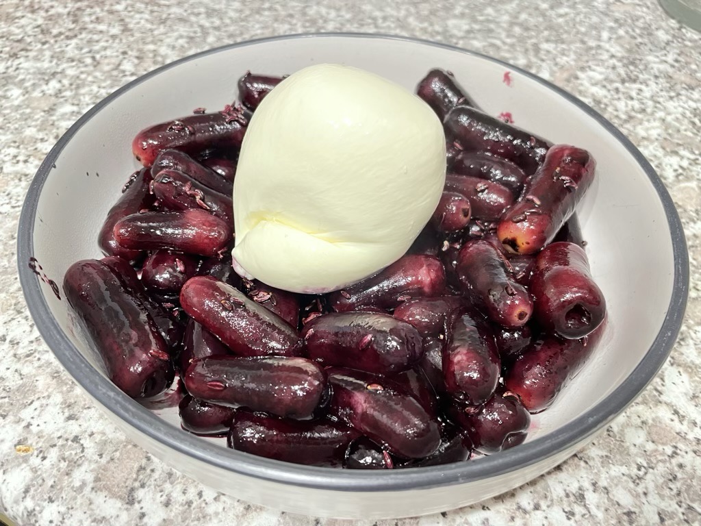 Grilled grapes and burrata arranged in white bowl