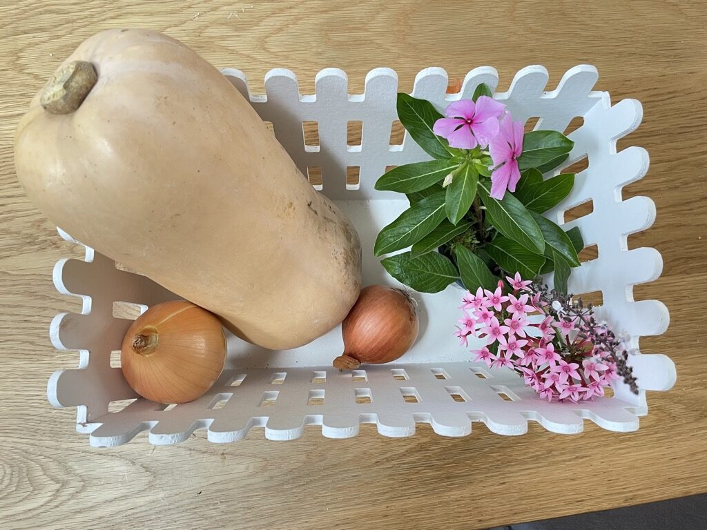 White basket with butternut squash, onions and pink flowers