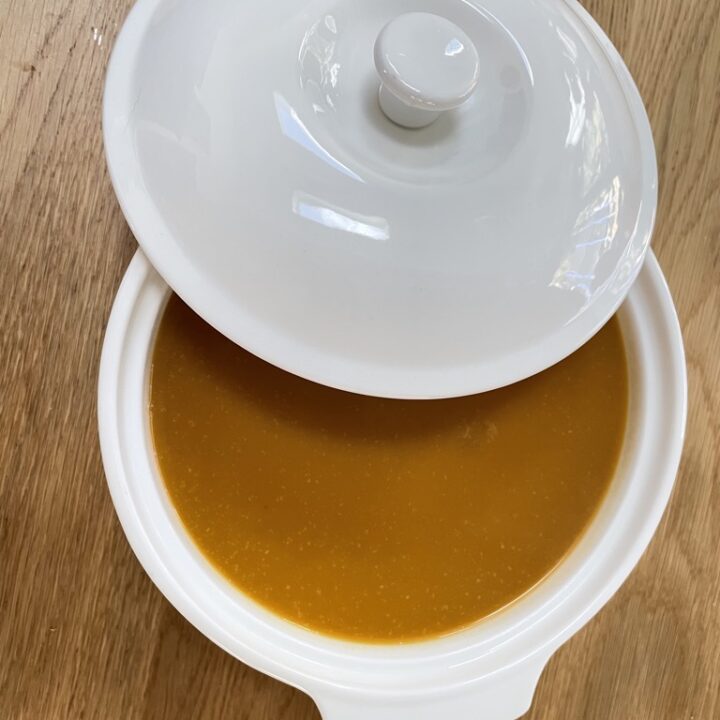 White serving bowl with lid half on showing butternut squash soup