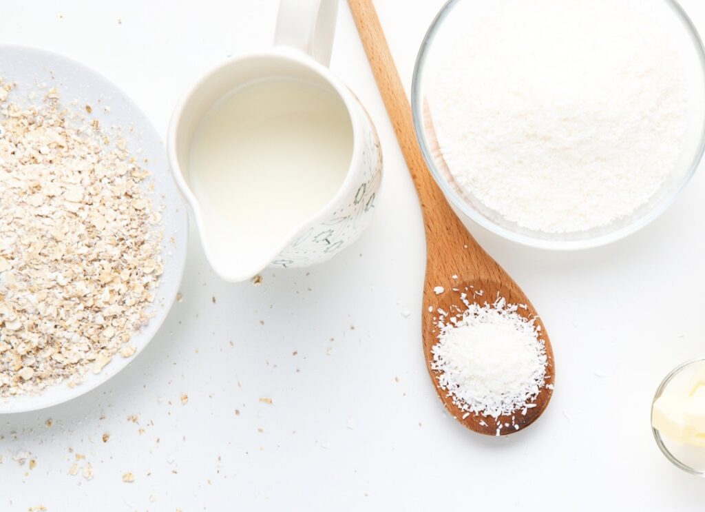 Oats, milk and wooden spoon with salt on white backdrop