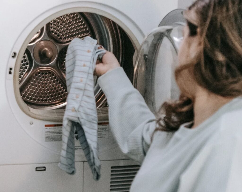 Woman putting baby onesie into washing machine