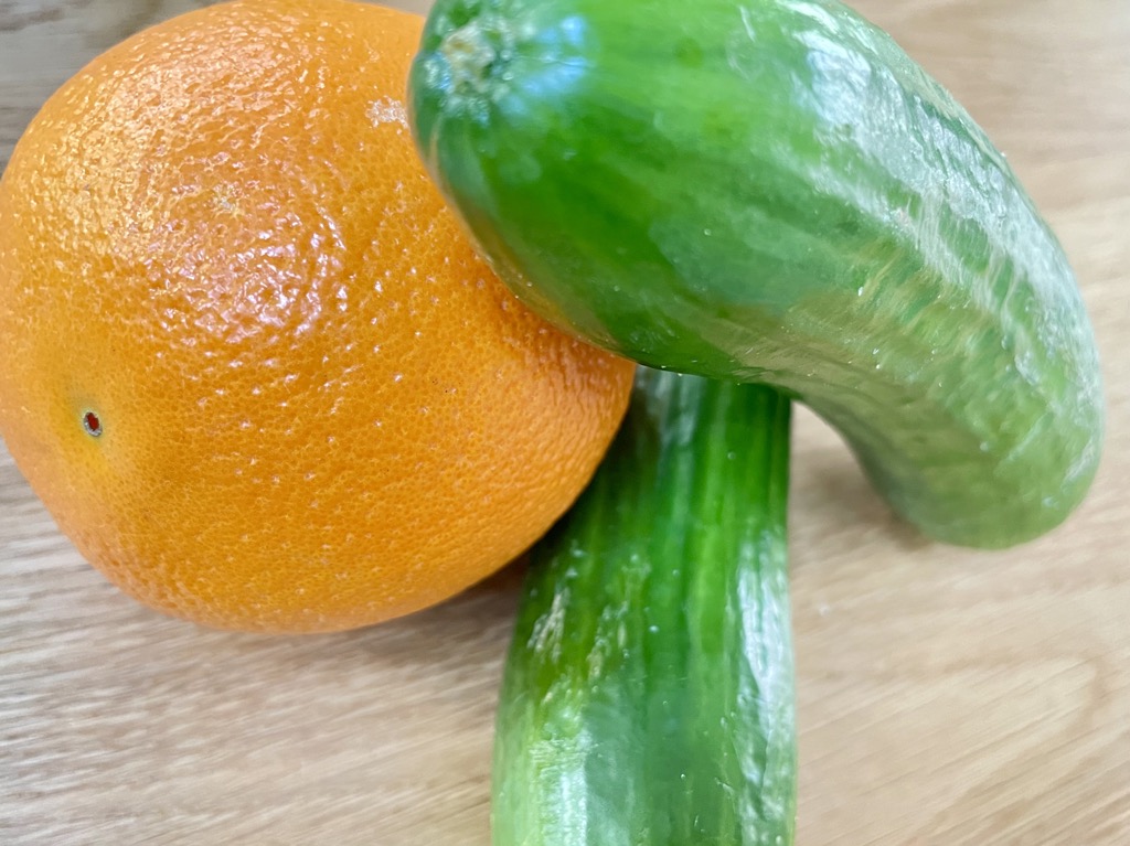 Two lebanese cucumbers and orange on wood