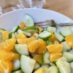 Fresh Cucumber and Orange Salad In a white bowl with silver fork