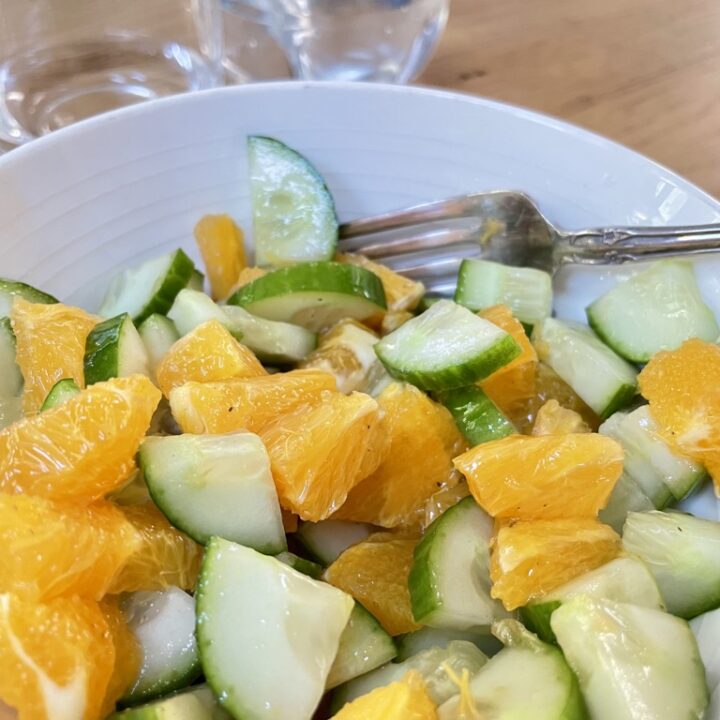 Fresh Cucumber and Orange Salad In a white bowl with silver fork