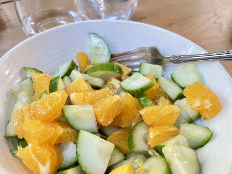 Fresh Cucumber and Orange Salad In a white bowl with silver fork