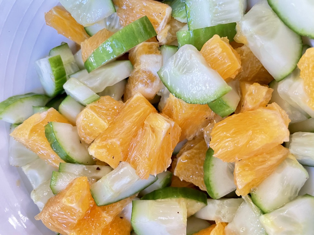 Close up shot of Fresh Cucumber and Orange Salad In white bowl