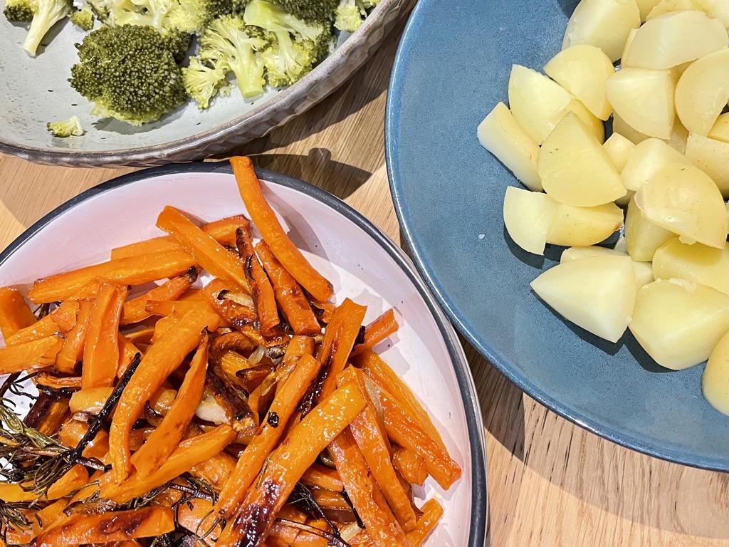 Three bowls filled with broccoli, potatoes and roasted carrots