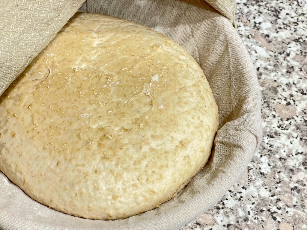 Proofing basket with risen loaf on benchtop