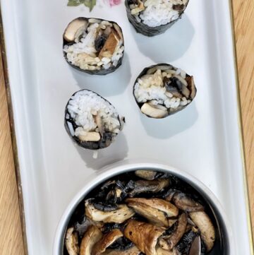 White platter with cream bowl of mushrooms next to four pieces of mushroom sushi