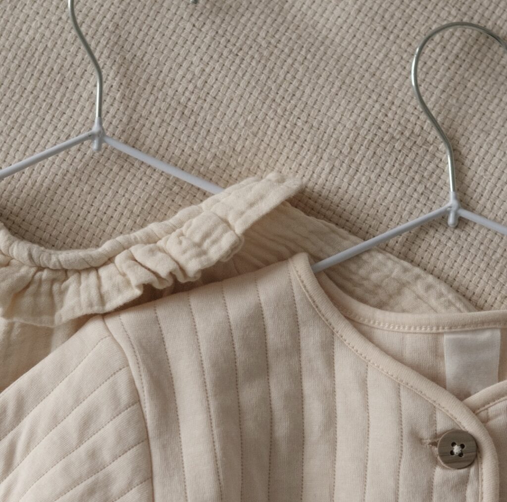 Cream newborn clothes on wire hangers