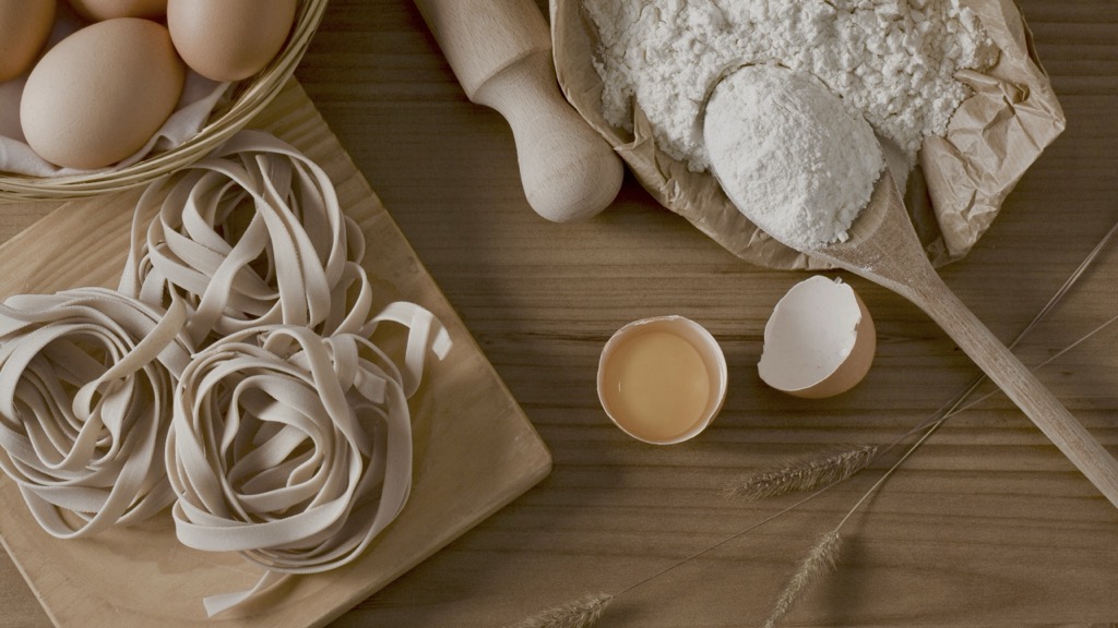 Fresh pasta, eggs and flour on wooden table