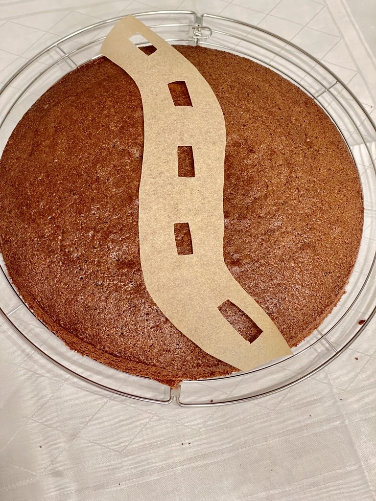 road stencil placed over plain cake