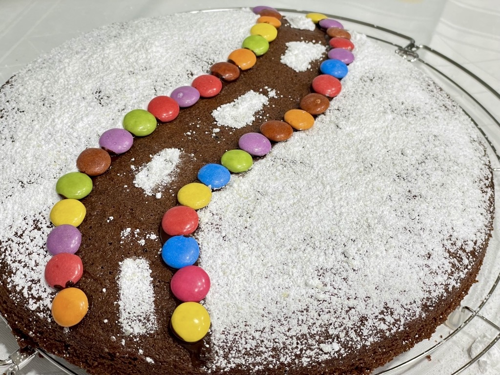 Cake decorated in powdered sugar and smarties shaping road design through middle