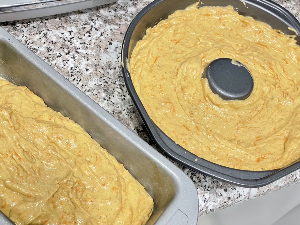 Unbaked sourdough discard carrot cakes in cake tins on kitchen counter