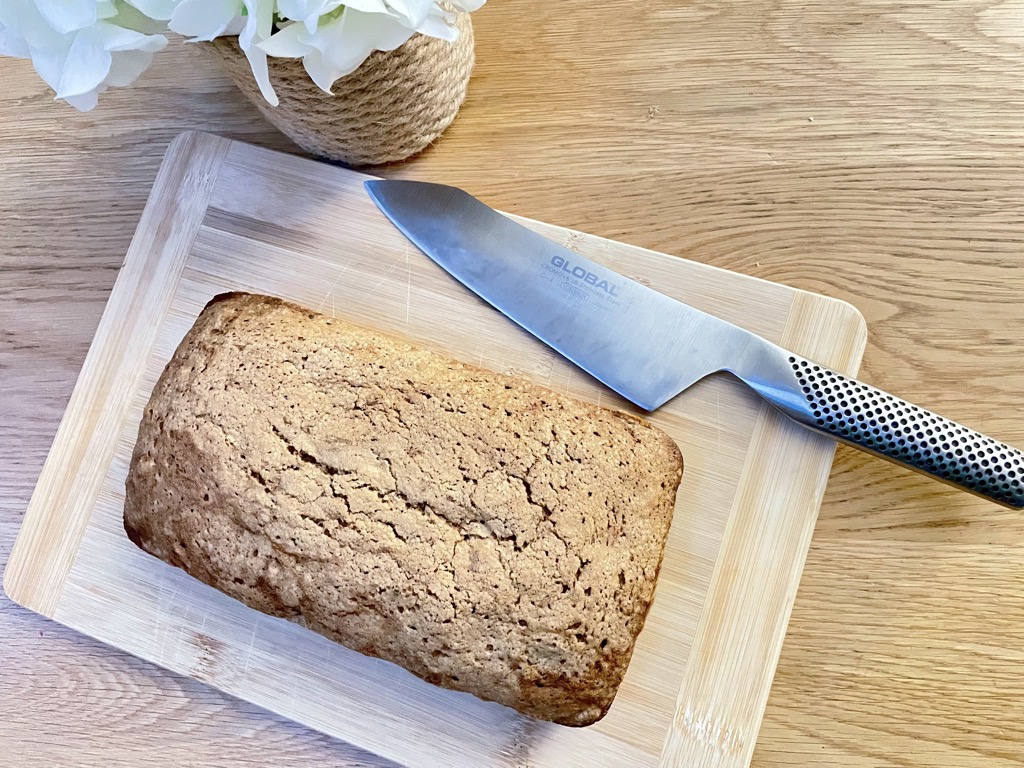 Sourdough discard zucchini bread on wooden board with silver knife and flowers