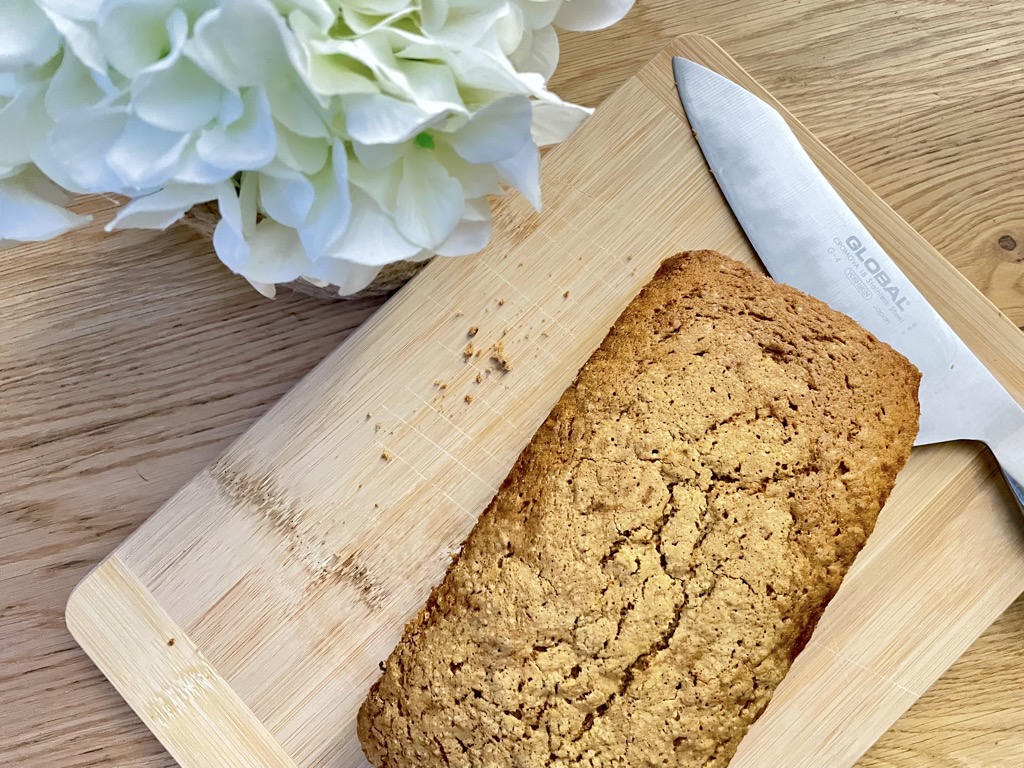 sourdough discard carrot cake without frosting On wooden board with knife and white flowers