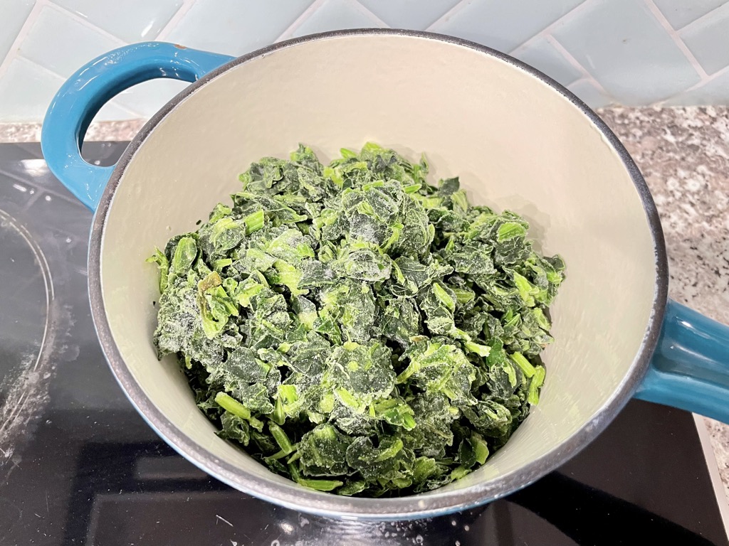 Sauce pan with frozen spinach on stove