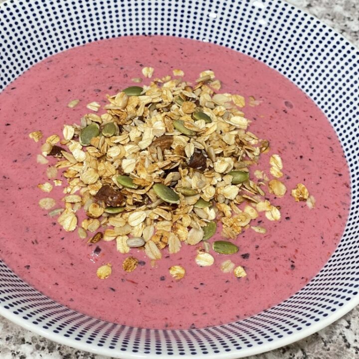 Bowl filled with pink smoothie and topped with granola