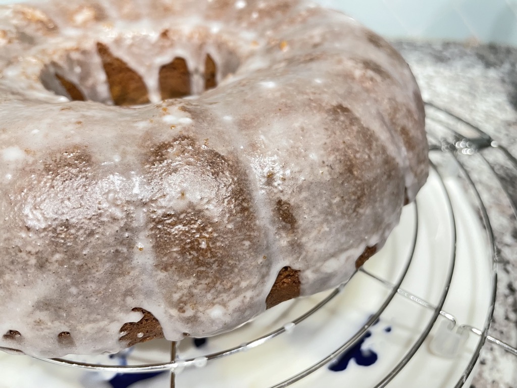 Close up shot of white iced bundt cake on silver cooling rack