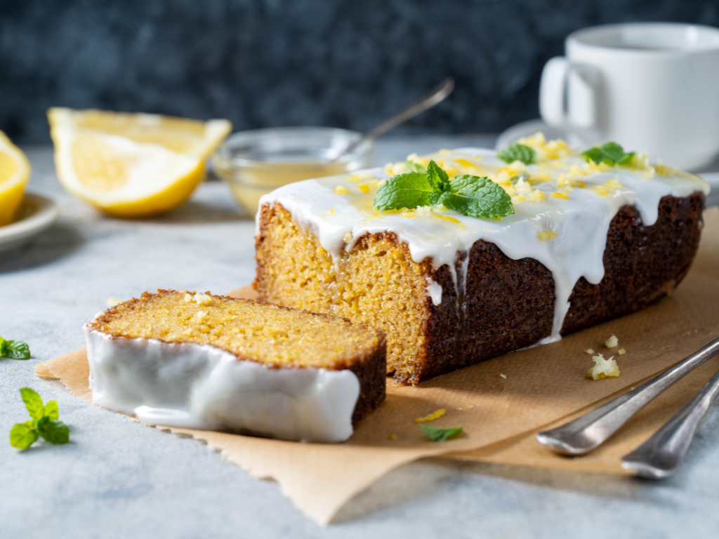 Lemon drizzle cake with lemon shavings and mint on baking paper